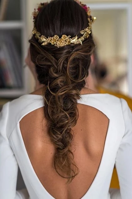Novia con peinado de trenza y corona de flores, mostrando las tendencias de peinados para bodas esta temporada.
